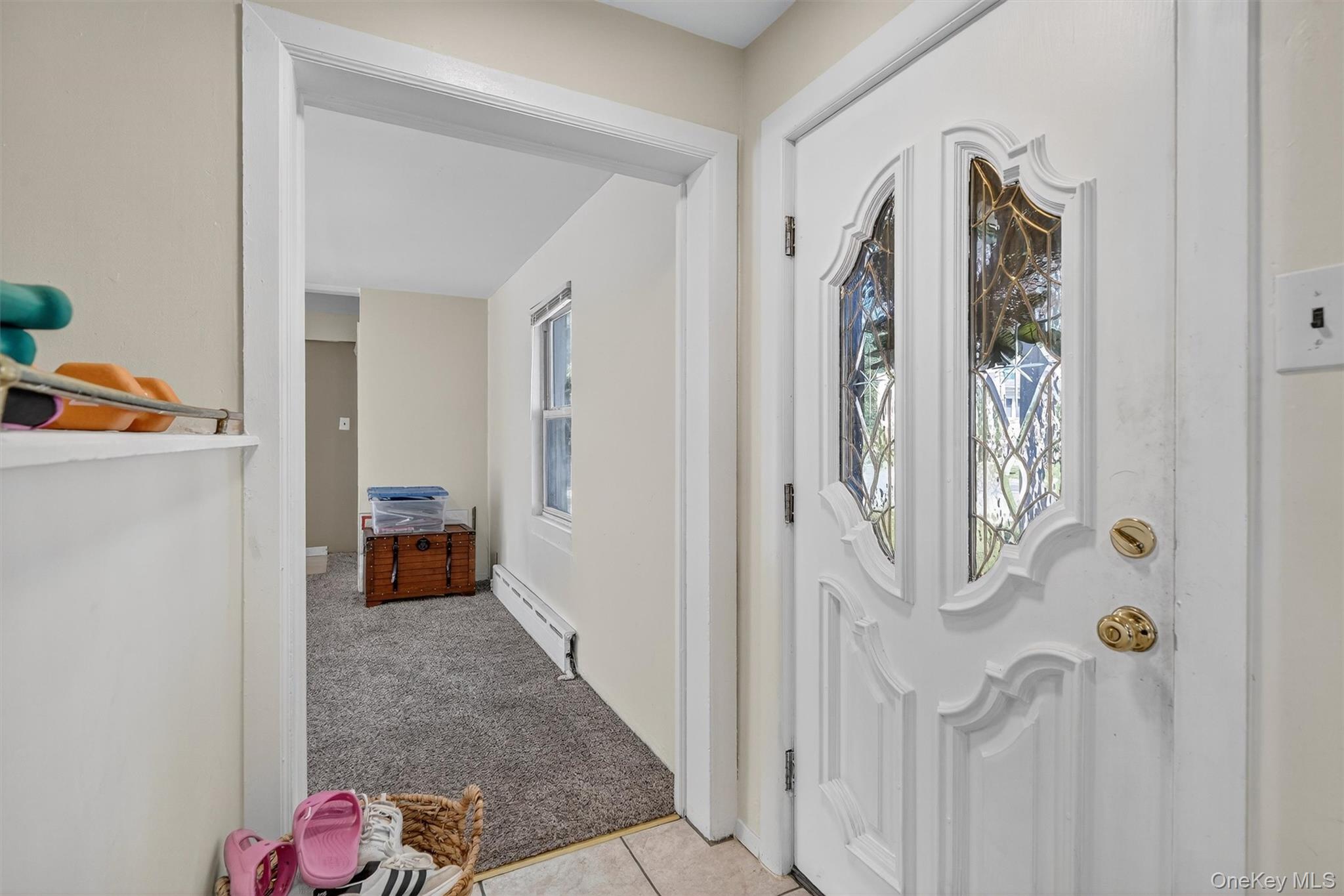 3384 Country Club Road Bronx, NY 10465 - Photo 5 of 48 Foyer entrance featuring light carpet, plenty of natural light, a baseboard heating unit, and light tile patterned floors