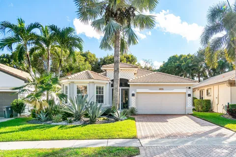 a front view of a house with a garden and palm trees
