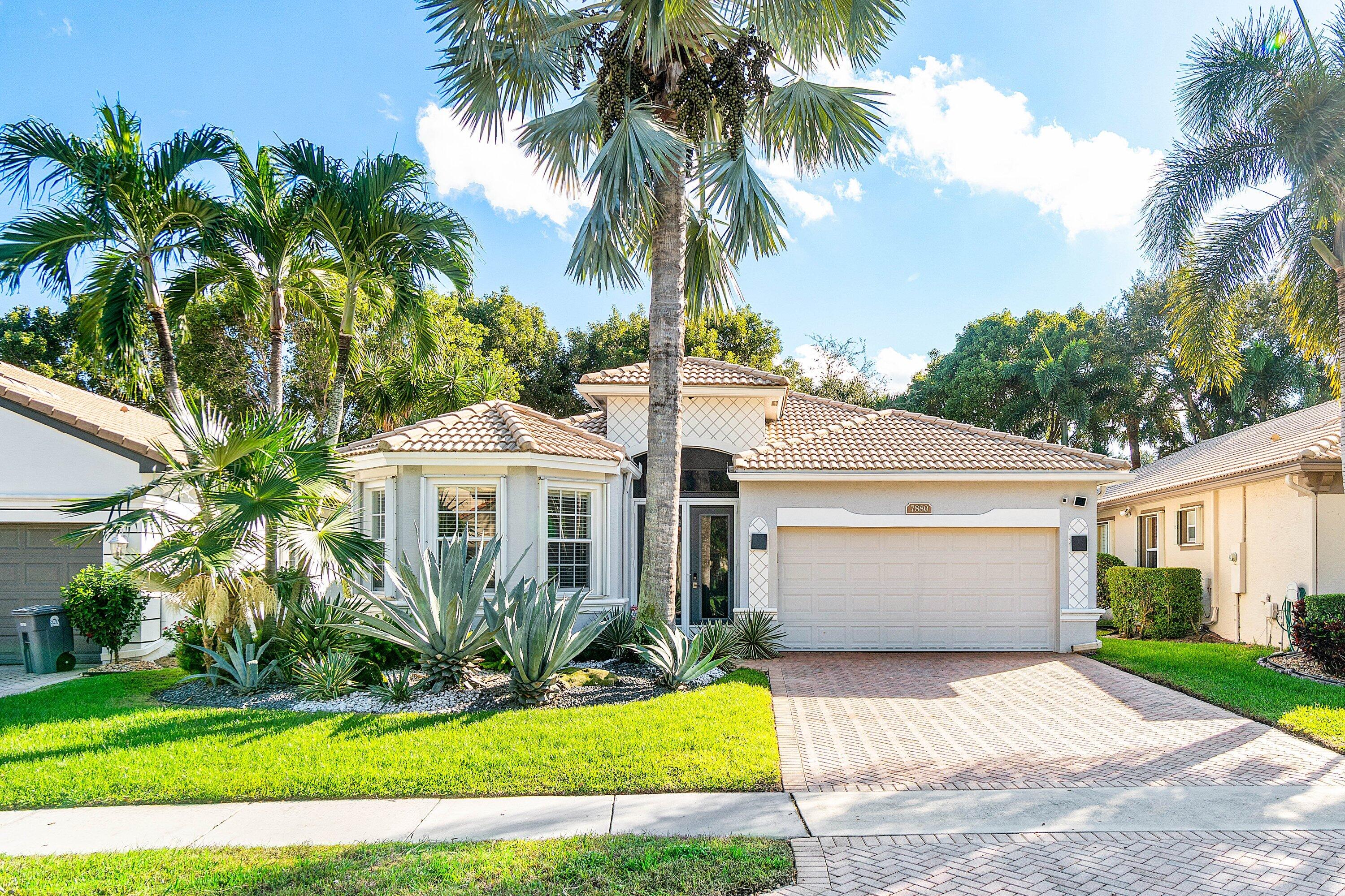 a front view of a house with a garden and palm trees