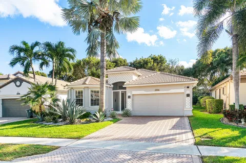 a view of a white house with a yard and palm trees