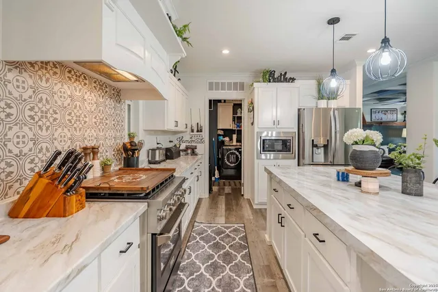 a kitchen with stainless steel appliances kitchen island granite countertop a sink stove and refrigerator