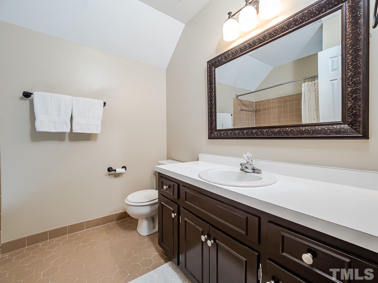 6933 Glendower Road Raleigh, NC 27613 - Photo 22 of 25 a bathroom with a granite countertop toilet sink and mirror