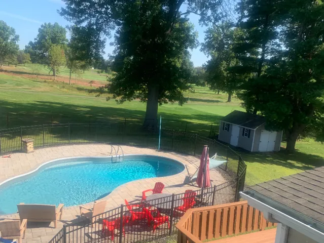 a view of swimming pool with lawn chairs and a yard