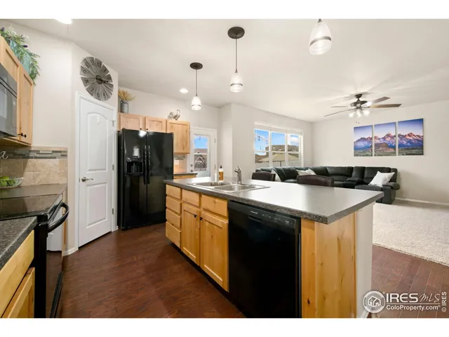a kitchen with stainless steel appliances granite countertop a refrigerator a sink a stove and a wooden cabinets