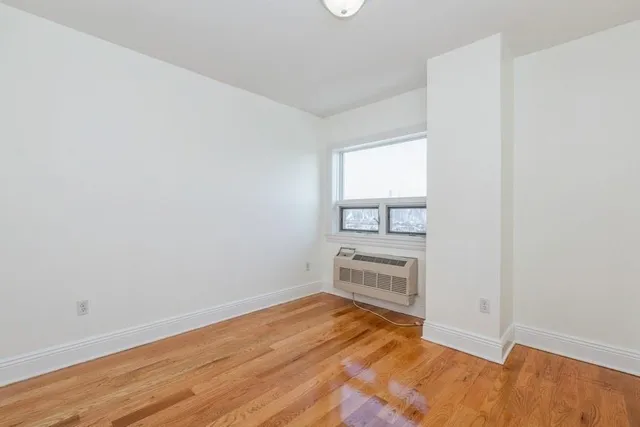 an empty room with wooden floor cabinet and windows