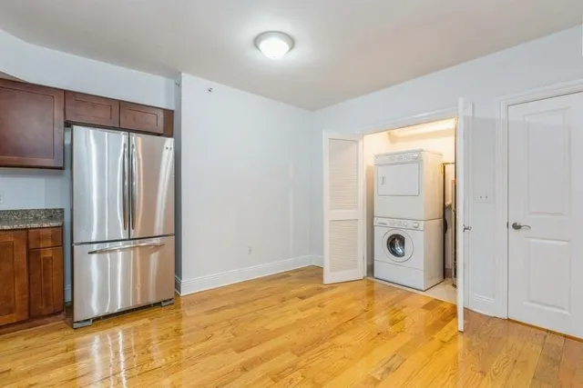 a view of a livingroom with wooden floor and a kitchen