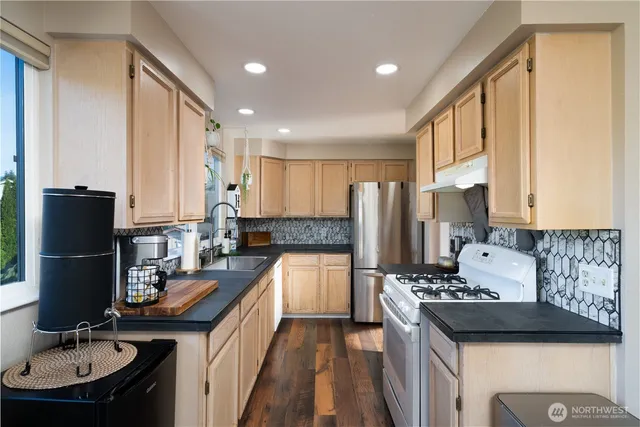 a kitchen with a sink a counter top space and living room view