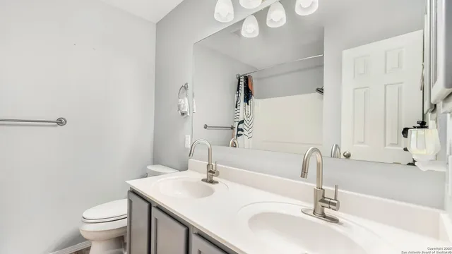 a bathroom with a sink a toilet and a large mirror