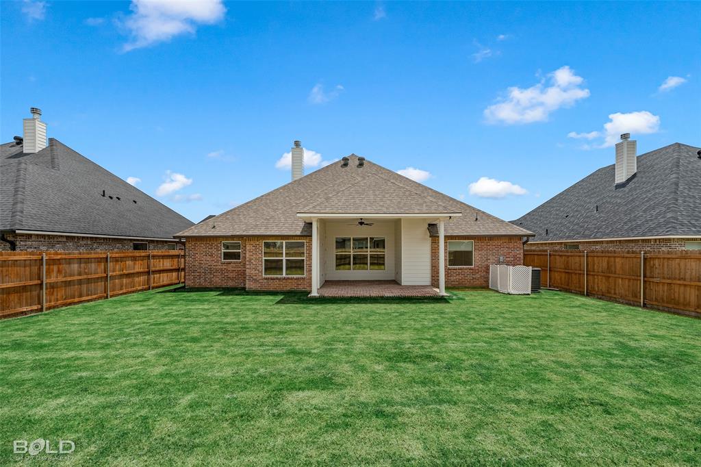 304 Prien Lk Loop Bossier City, LA 71111 - Photo 34 of 39 Expansive green lawn with a covered patio, brick exterior, wood fence, and a visible HVAC unit