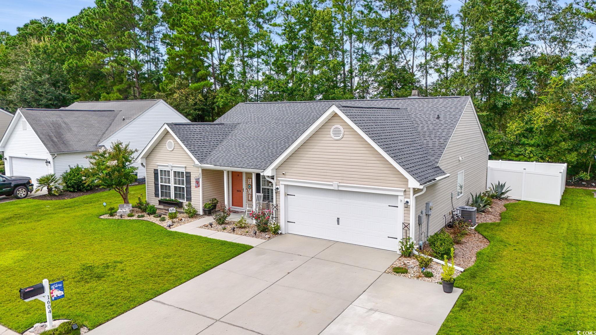 1604 Langley Drive Longs, SC 29568 - Photo 2 of 37 View of front facade featuring roof with shingles, driveway, a garage, covered porch, and view of scattered trees