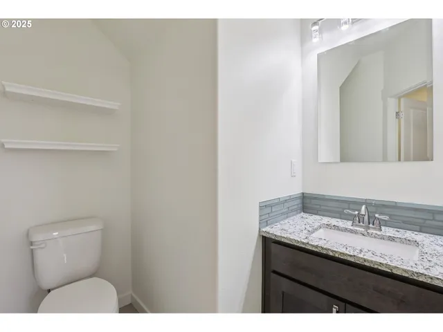 a bathroom with a granite countertop sink a toilet and a mirror