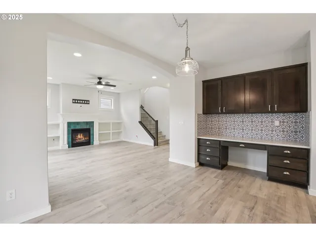 a view of living room kitchen with a fireplace wooden floor and cabinets