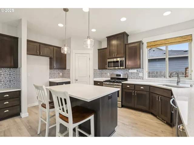 a kitchen with stainless steel appliances kitchen island granite countertop a sink stove and refrigerator