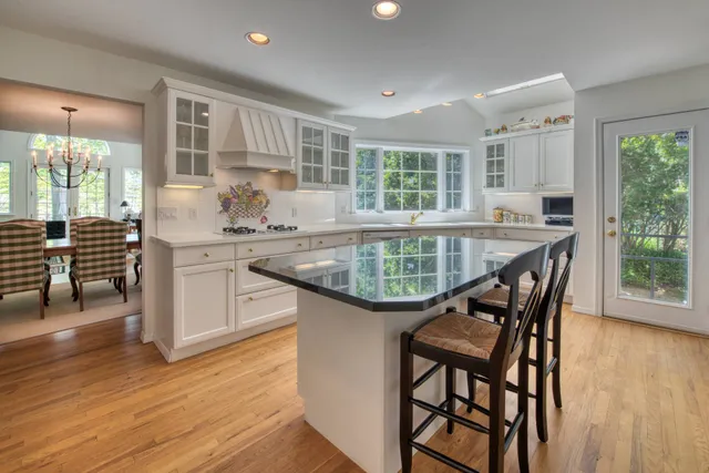 a kitchen with stainless steel appliances granite countertop a kitchen island hardwood floor sink stove dining table and chairs