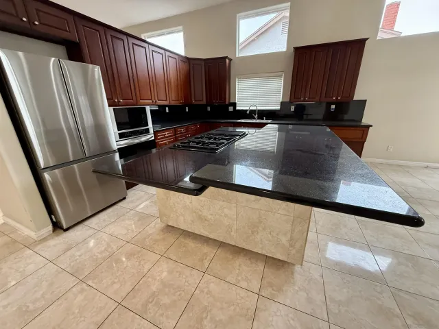 a kitchen with stainless steel appliances a sink a stove a refrigerator a sink a counter top space and cabinets