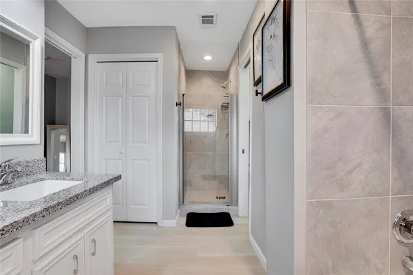 a bathroom with a granite countertop shower a sink and a mirror
