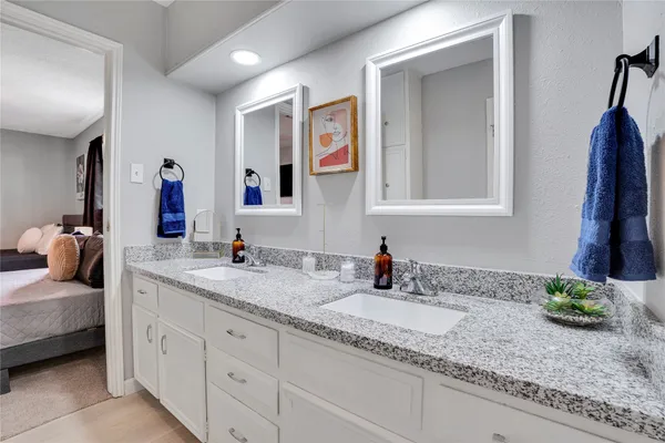 a bathroom with a granite countertop double vanity sink and a mirror