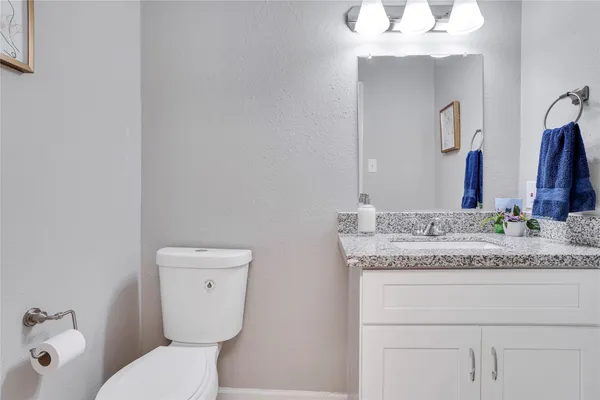 a bathroom with a granite countertop toilet sink and mirror