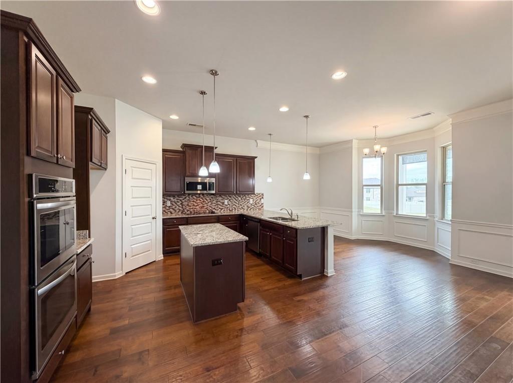 1549 Harlequin Way Stockbridge, GA 30281 - Photo 12 of 30 a kitchen with stainless steel appliances kitchen island granite countertop a stove a refrigerator a sink a oven with wooden cabinets and wooden floor