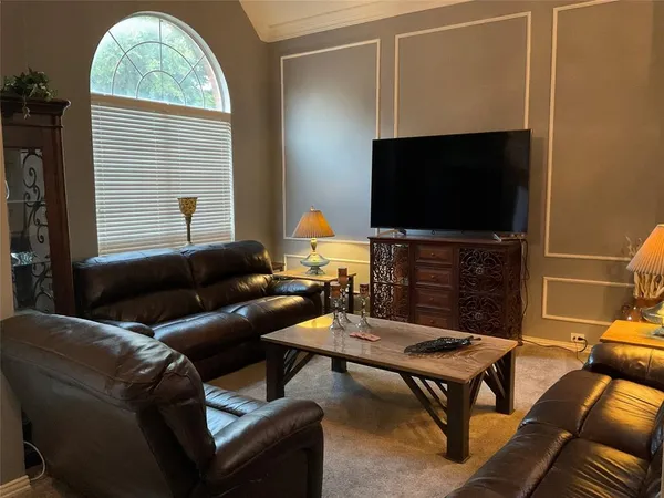 a living room with furniture a flat screen tv and a window