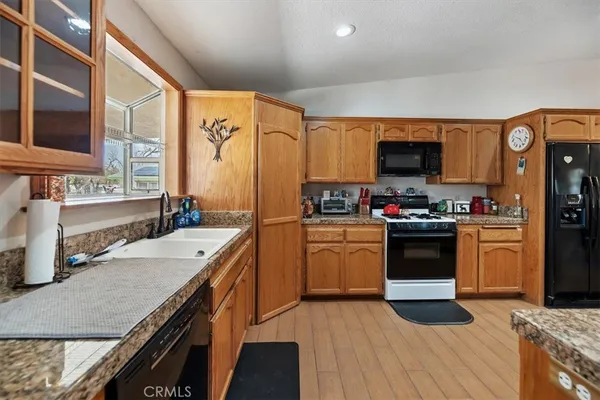 a kitchen with stainless steel appliances granite countertop a sink dishwasher a stove and a refrigerator with wooden floor