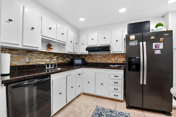 a kitchen with stainless steel appliances granite countertop a sink and a refrigerator