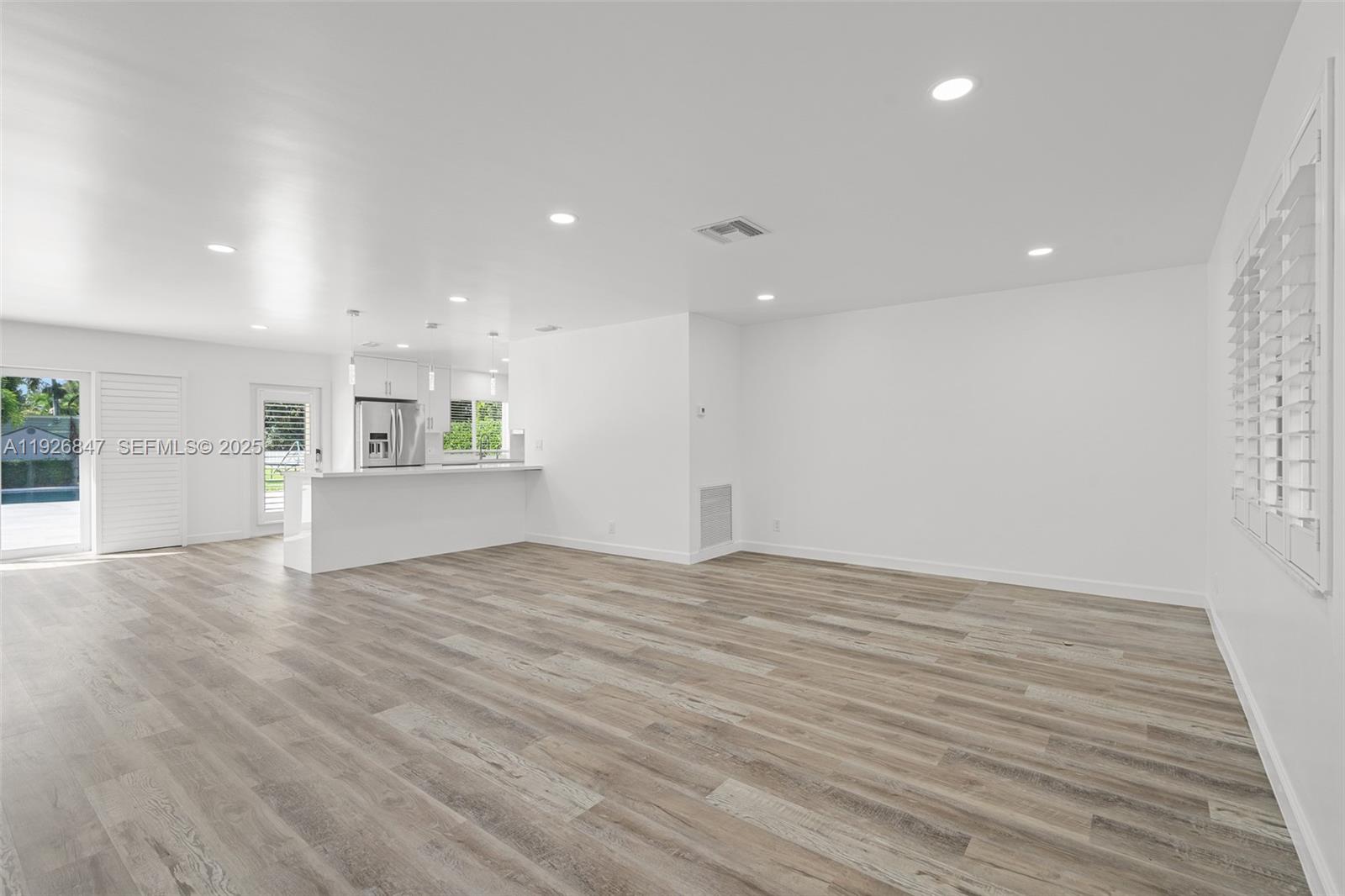 14330 Southwest 16th Street Davie, FL 33325 - Photo 8 of 53 a view of an empty room with wooden floor and a kitchen