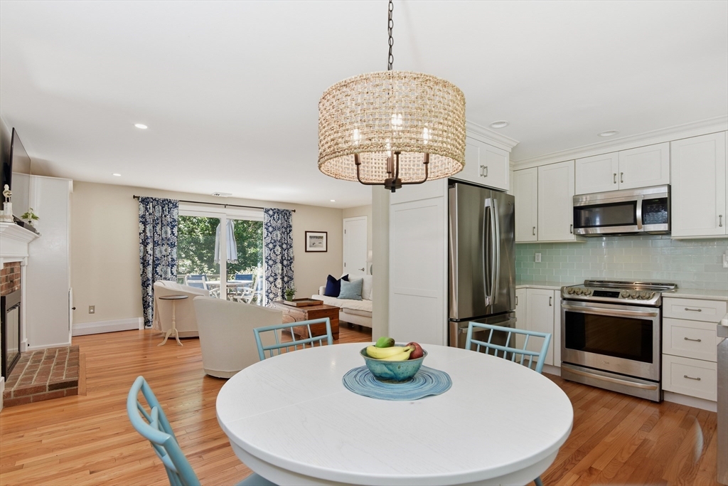 8 Emerald Way Sandwich, MA 02644 - Photo 4 of 36 a kitchen with stainless steel appliances granite countertop a stove a kitchen island a refrigerator a stove a dining table and chairs with wooden floor