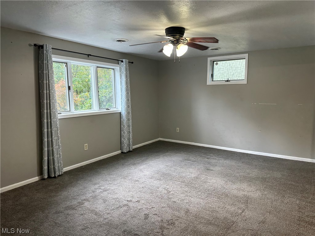 6715 Crosse Road Amherst, OH 44001 - Photo 13 of 21 Spare room with a textured ceiling, dark colored carpet, and ceiling fan