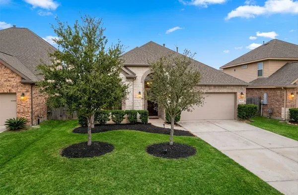 a front view of a house with garden and trees