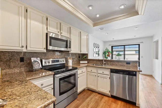 a kitchen with stainless steel appliances granite countertop a stove a sink and a microwave