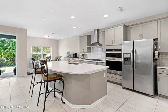 a kitchen with stainless steel appliances kitchen island a table chairs and a refrigerator