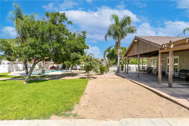 a view of a pathway of a house with potted plants and large trees