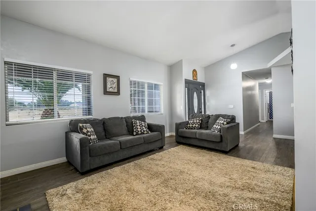 a living room with stainless steel appliances kitchen island granite countertop furniture and a wooden floor