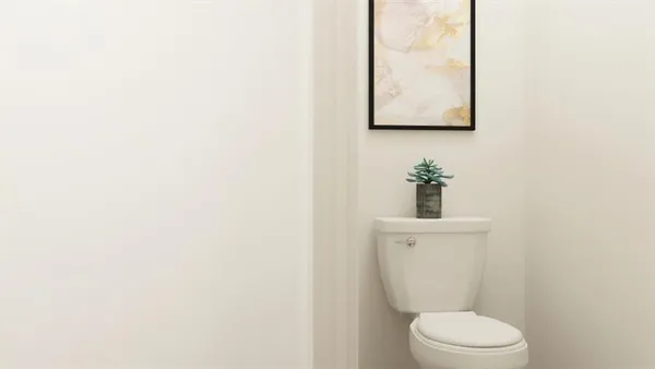 a white toilet sitting next to a white wall