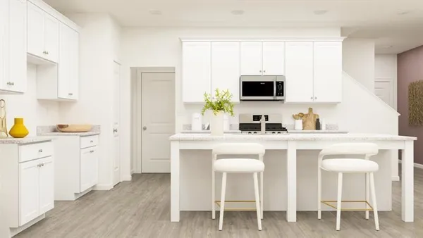 a kitchen with white cabinets and chair