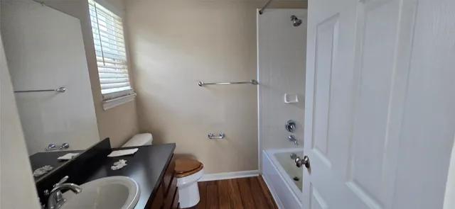 a bathroom with a granite countertop bathtub shower sink vanity and a toilet