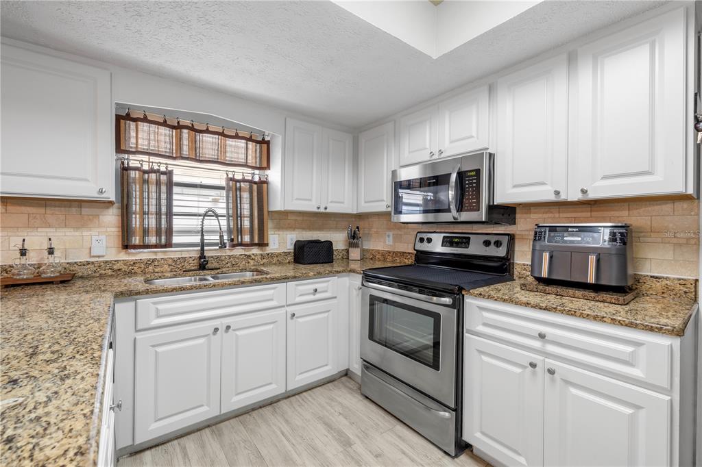 1005 Mook Street Brandon, FL 33510 - Photo 17 of 48 a kitchen with granite countertop white cabinets sink and stainless steel appliances