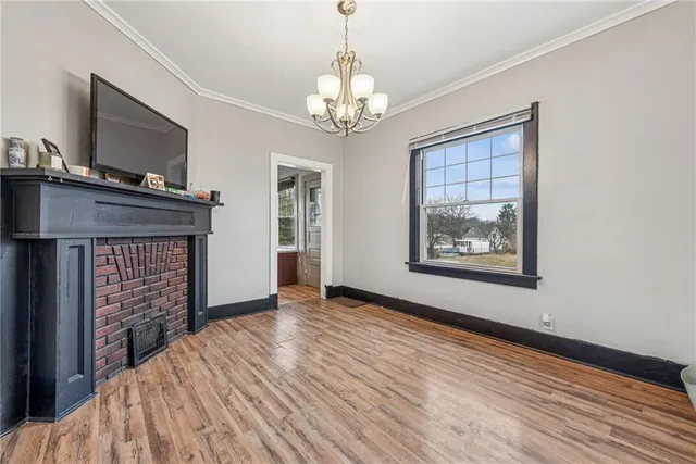 a view of an empty room with wooden floor fireplace and a window