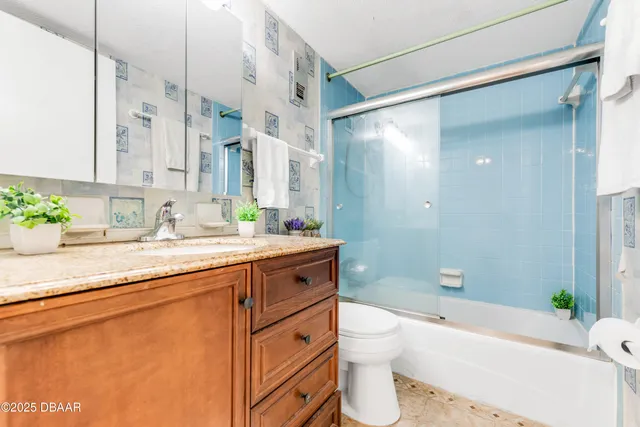 a bathroom with a granite countertop sink a toilet a mirror a bathtub and shower