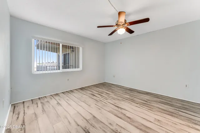 a view of empty room with wooden floor and fan