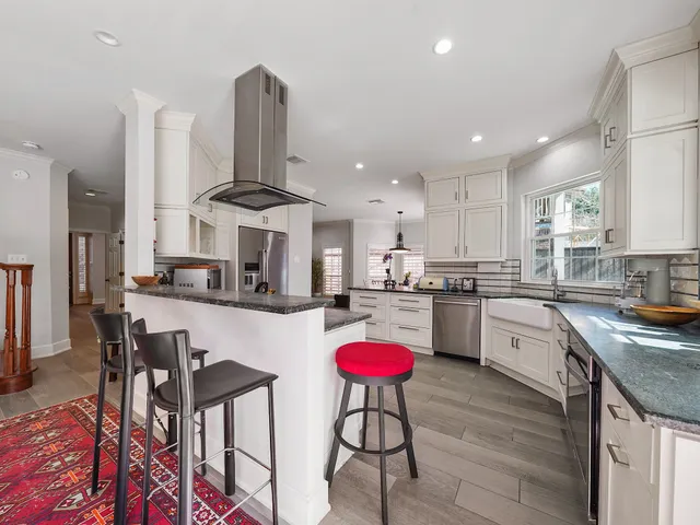 a kitchen with stainless steel appliances granite countertop a stove top oven a sink dishwasher and white cabinets with wooden floor