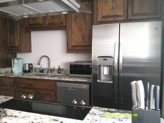a kitchen with granite countertop a refrigerator and a sink