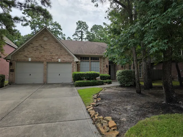 a view of a house with a yard plants and large tree