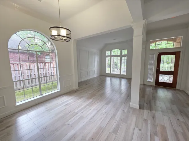 an empty room with wooden floor fan and windows