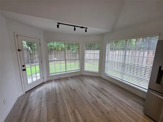 a view of an empty room with wooden floor and a window