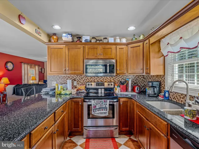 a kitchen with stainless steel appliances granite countertop a stove a sink and a microwave