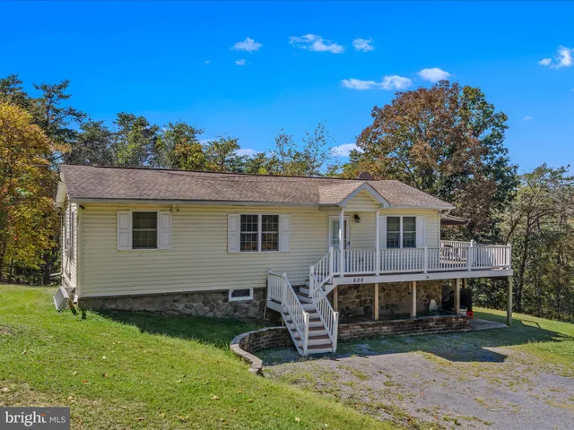 a front view of house with yard and trees in the background