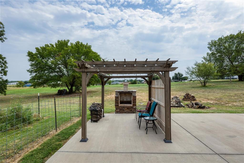 210 Spring Branch Trail North Springtown, TX 76082 - Photo 20 of 36 Expansive concrete patio featuring a wood pergola, stone outdoor fireplace, and a partial wood privacy screen