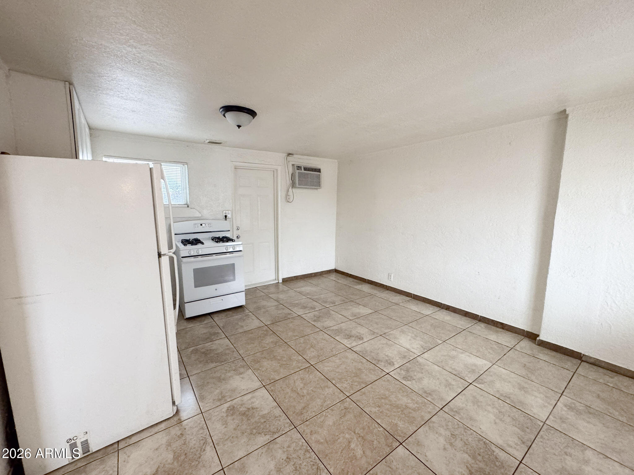 3601 West Melvin Street, Unit 7 Phoenix, AZ 85009 - Photo 3 of 26 a view of a refrigerator in kitchen and white cabinets